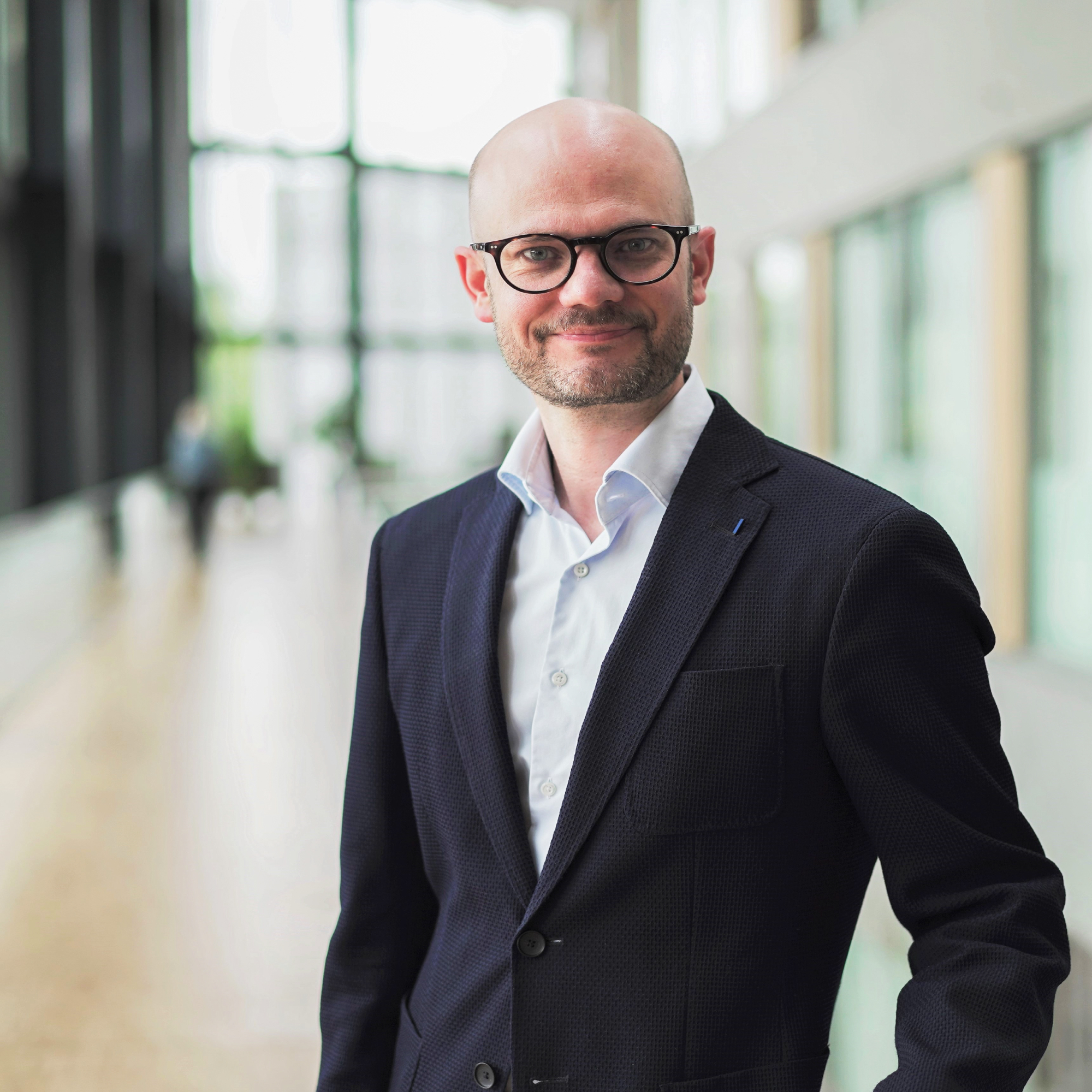 Man i kostym och glasögon i modern kontorsmiljö