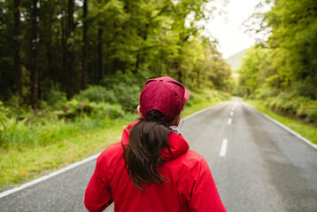 Person som joggar på en landsväg omgiven av grönskande skog