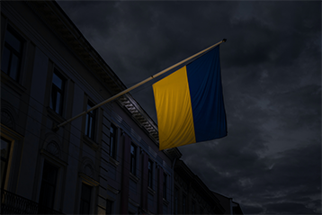 Ukrainas flagga vajande utanför en byggnad på kvällen, mot en mörk himmel