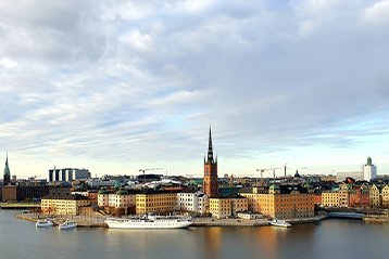 Panoramautsikt över Gamla stan i Stockholm med Riddarholmskyrkan i bakgrunden och båtar längs kajen