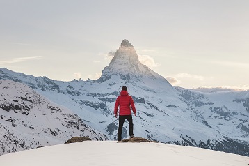 Person står på snötäckt bergstopp med vy över Matterhorn, Schweiz