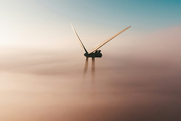 Vindkraftverk ovanför molntäcke i solnedgång