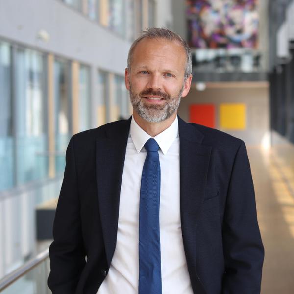 Man i kostym står i en modern kontorsmiljö